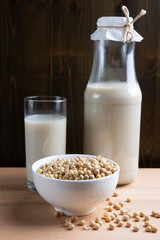 Glass of Soy milk and bottle and organic soy seeds on wooden background, Alternative Milk
