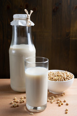 Glass of Soy milk and bottle and organic soy seeds on wooden background, Alternative Milk