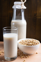 Glass of Soy milk and bottle and organic soy seeds on wooden background, Alternative Milk