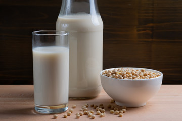 Glass of Soy milk and bottle and organic soy seeds on wooden background, Alternative Milk