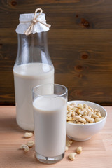 Glass of Cashew milk and bottle and organic cashew on wooden background, Alternative Milk. Nuts milk