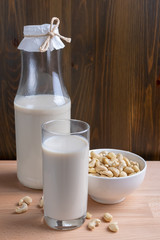 Glass of Cashew milk and bottle and organic cashew on wooden background, Alternative Milk. Nuts milk
