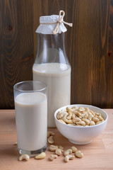Glass of Cashew milk and bottle and organic cashew on wooden background, Alternative Milk. Nuts milk