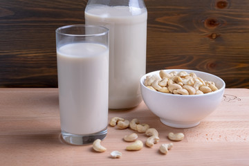 Glass of Cashew milk and bottle and organic cashew on wooden background, Alternative Milk. Nuts milk