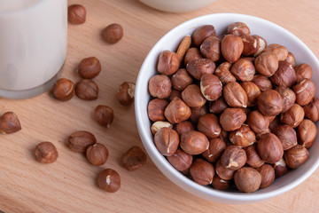 Glass of Hazelnut milk and bottle and organic hazelnuts on wooden background, Alternative Milk. Nuts milk