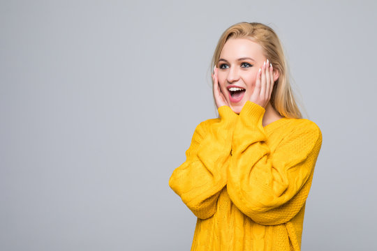 Portrait of surprised woman in sweater looking at the camera over gray background