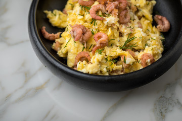 Krabben Rührei mit Friesischen Nordseekrabben und Dill in schwarzer Schale auf Marmor Hintergrund