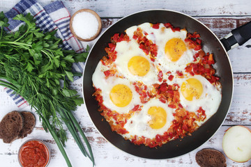 Shakshouka with five cooked eggs on top of tomato sauce in cast iron skillet