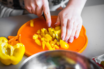 Frau in der küche schneidet gelbe Paprika für salat 