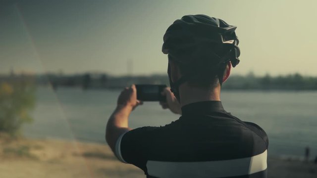 Cyclist Taking Photo With Smartphone During Biking Cycling.Cyclist In Helmet Takes Picture On Mobile Phone.Close Up Cyclist Athlete Taking Photo.Portrait Bicyclist Taking Photo.Bicyclist Photographer