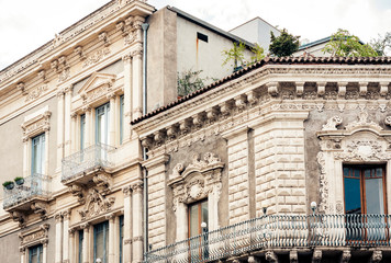 Balcony with flowerpots and house plants in a historic building in Catania, traditional architecture of Sicily, Italy.