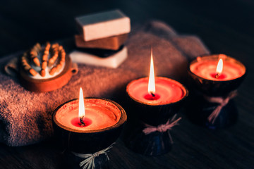 Burning spa aroma candles in coconut shell, handmade soap, towel and washcloth, spa concept background.