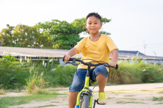 Asian Kid Boy Ride Bicycle In Nature