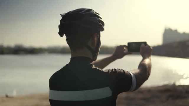 Cyclist Taking Photo With Smartphone During Biking Cycling.Cyclist In Helmet Takes Picture On Mobile Phone.Close Up Cyclist Athlete Taking Photo.Portrait Bicyclist Taking Photo.Bicyclist Photographer