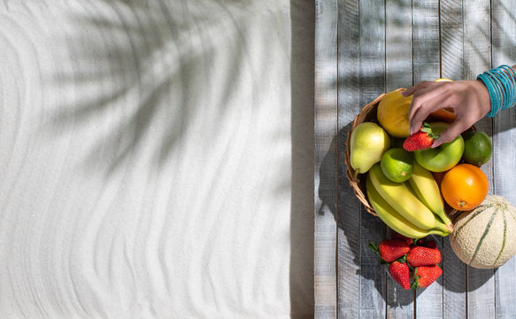 Woman lying on the beach and eating fruit