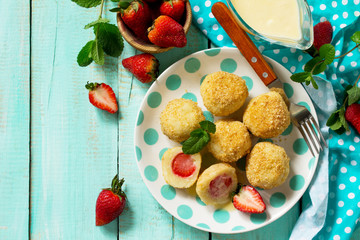 Cottage cheese dumplings with fresh strawberry, served with sour-honey sauce, delicious summer dessert on the kitchen wooden table. Top view flat lay background, copy space.
