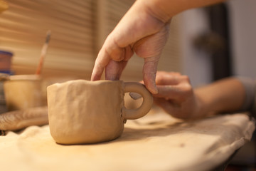 Female potter works with ceramic at his workshop. Young woman work inside 