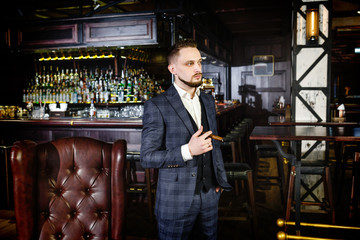 an influential businessman will buy a cigar in a bar. A man in a stylish suit smokes a cigar in a nightclub