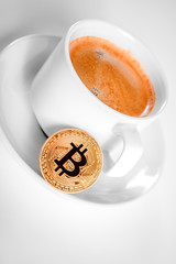 Cryptocurrency golden bitcoin standing on coffee cup isolated on a white background