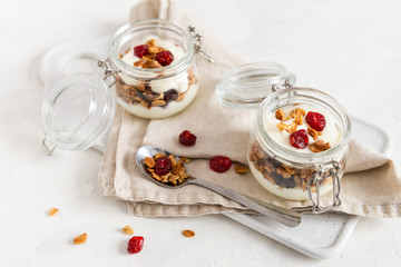 Homemade granola with nuts, fruits and yogurt in jars on white background. Healthy food, dieting. breakfast time. Copy space