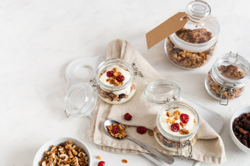 Crunchy honey granola in jars with flax seeds, cranberries, coconut, yogurt and cherry. Healthy, vegeterian fiber food. Breakfast time. Dieting concept for banner. Copy space