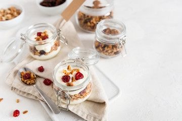 Obraz na płótnie Canvas Crunchy honey granola in jars with flax seeds, cranberries, coconut, yogurt and cherry. Healthy, vegeterian fiber food. Breakfast time. Dieting concept for banner. Copy space.