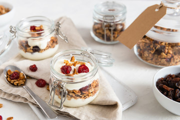 Homemade granola with nuts, fruits and yogurt in jars on white background. Healthy food, dieting. breakfast time. Copy space