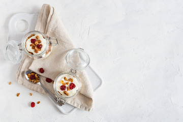 Obraz na płótnie Canvas Crunchy honey granola in jars with flax seeds, cranberries, coconut, yogurt and cherry. Healthy, vegeterian fiber food. Breakfast time. Dieting concept for banner. Copy space. Top view