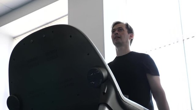 man on a treadmill goes, cardio load. fitness club man engaged in walking. strengthening the muscles of the heart and legs by walking. man trains on a treadmill. walking in gym. weight loss in gym.