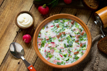 Delicious summer lunch. Spring-summer yoghurt cold soup  fresh vegetables and kefir on rustic wooden table.