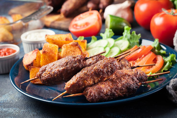 Grilled shish kebab served with fried potatoes