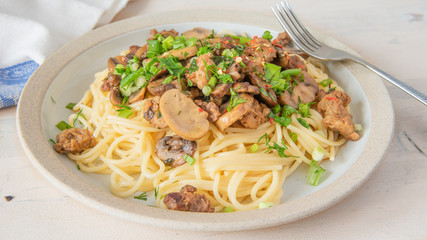 Spaghetti with homemade sausage and mushroom stew on a plate - traditional Italian pasta with Boscaiola mushroom sauce.