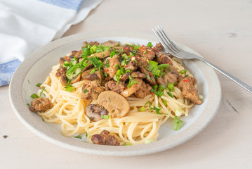 Spaghetti with homemade sausage and mushroom stew on a plate - traditional Italian pasta with Boscaiola mushroom sauce.