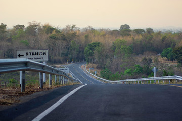 Naklejka premium The road has a yellow line and there is a warning sign on the steep left side down from him.