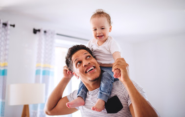 Father and small toddler son indoors at home, playing.