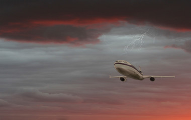 Fototapeta na wymiar Airplane with dramatic sky and lightning, flying at bad weather with dark clouds