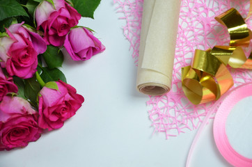 Florist at work: pretty woman making summer bouquet of roses on a working table. Kraft paper, scissors, envelope for congratulations on the table. View from above. Flat lay composition.