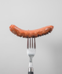 sausage on fork isolated over white background