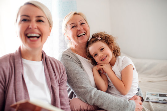 A small girl with mother and grandmother at home, laughing.
