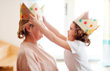 A portrait of small girl with grandmother at home, having fun.
