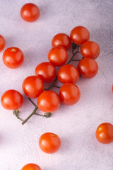 Bunch of cherry tomatoes on white textured stone concrete table, top view with copy space. Ingredients for cooking.