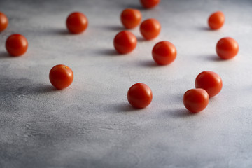 Cherry tomatoes scattered across white textured stone concrete table, with copy space. Ingredients for cooking.