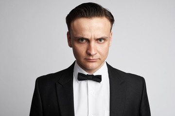 Fashionable young man wearing suit and bow tie. Angry guy isolated