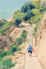 Young man in a hat goes down the stairs to the sea