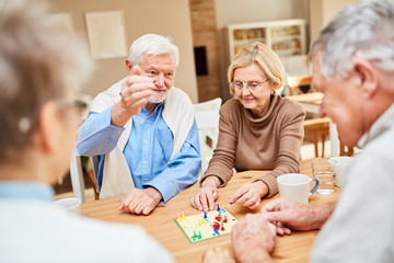 Rentner Paar spielt mit Freunden Brettspiel