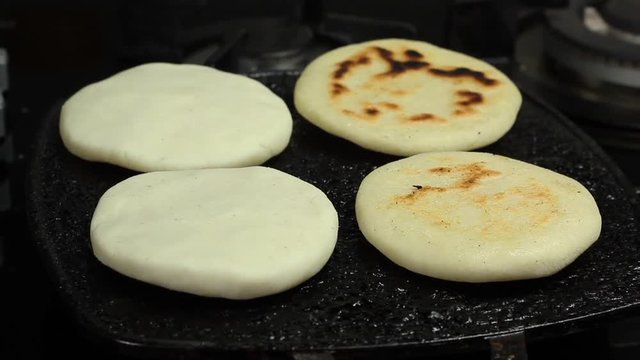 hands removing roasted arepa stove, traditional venezuelan food arepa preparation.