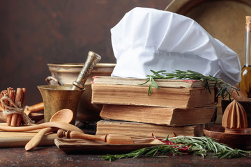  Old kitchen utensils with spices and rosemary on a kitchen table.