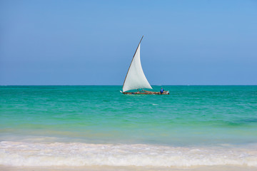 Fisherman sitting in dhow boat sailing blue waters