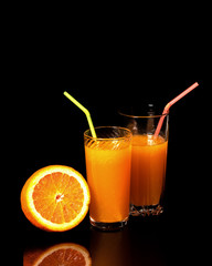Glass with fresh orange juice and orange on a black background