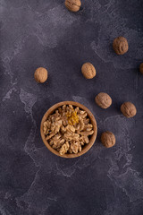 Cracked and whole walnuts in wooden bowl and on blue slate surface. Healthy nuts and seeds composition.